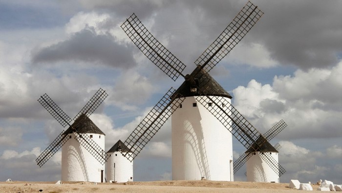 White windmills with black roofs and sails under a cloudy sky