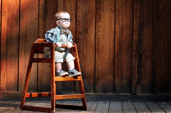 Baby boy in glasses and bow tie sitting in a high chair