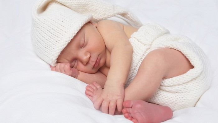 Newborn baby sleeping in a knitted outfit