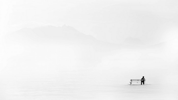 Man sitting on a bench in a foggy winter landscape