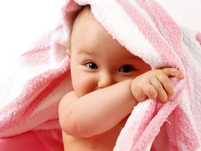 Baby peeking from under a pink and white striped towel