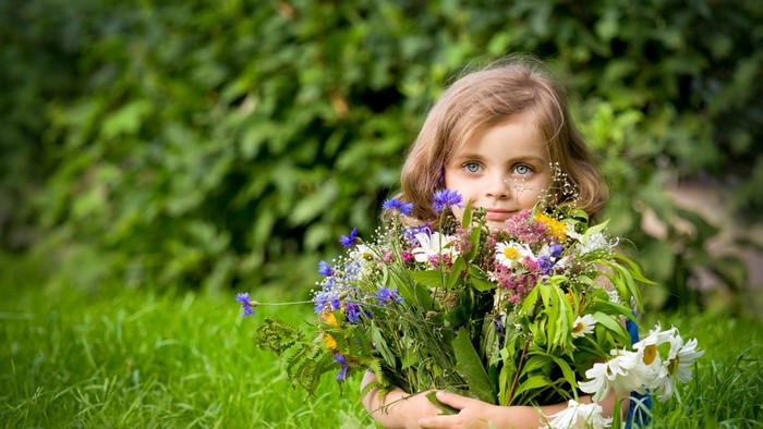 Young girl holding a bouquet of wildflowers in a garden