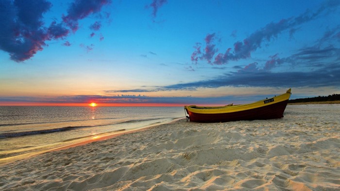 Boat on a sandy beach at sunset