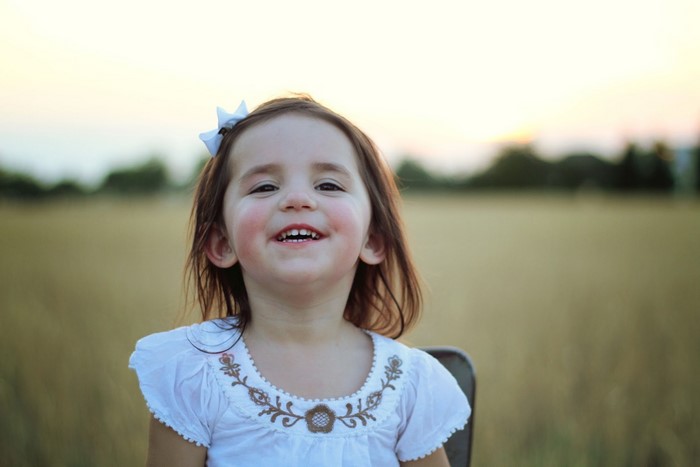 A smiling young girl with a white bow in her hair