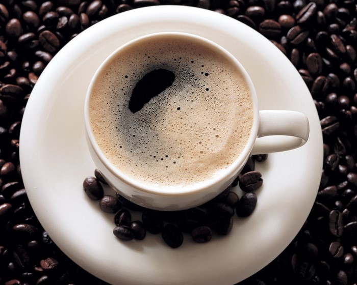 Cup of coffee on a saucer with coffee beans