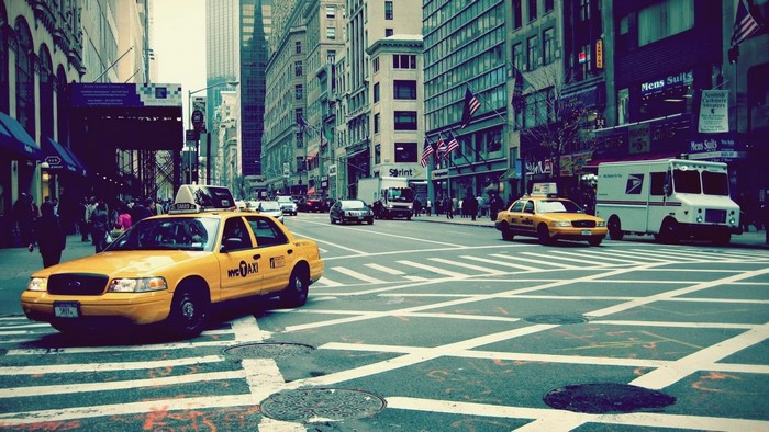 Yellow NYC Taxi and USPS Truck on a City Street