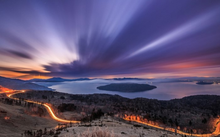 Long exposure of a winding road and misty lake at dusk
