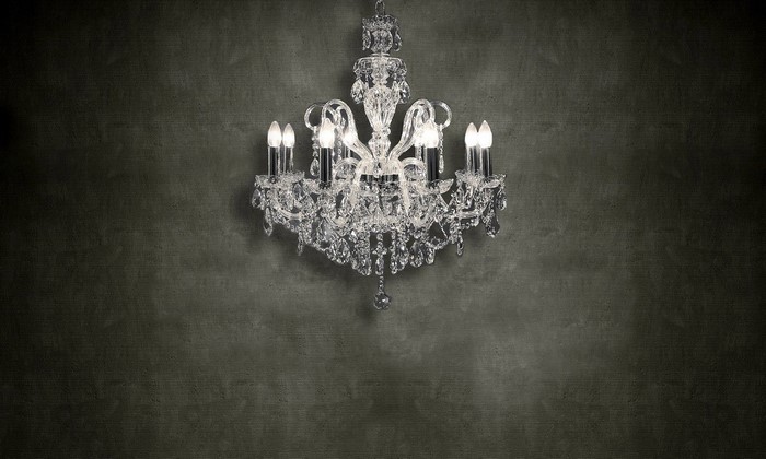 Crystal chandelier with candle-shaped lights on a dark textured wall