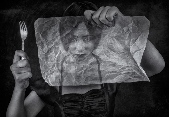 Woman holding a fork behind crumpled paper