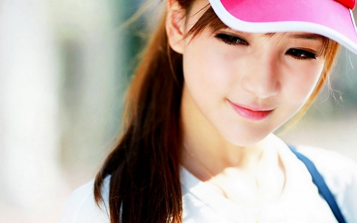 Close up portrait of a young Asian woman wearing a pink visor
