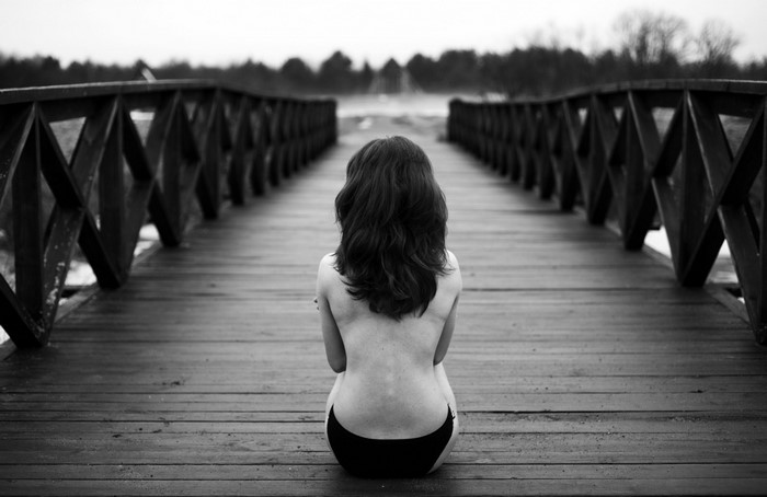 Woman sitting on a wooden bridge