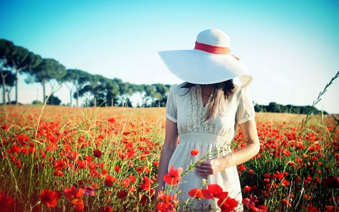 Woman in a wide-brimmed hat in a poppy field