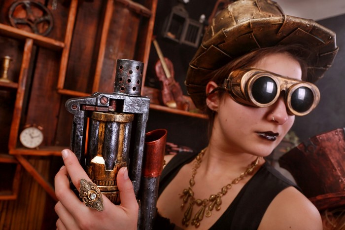 Woman in Steampunk attire with goggles and weapon