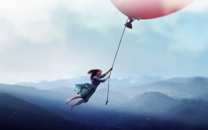 Girl flying with a pink balloon over mountains