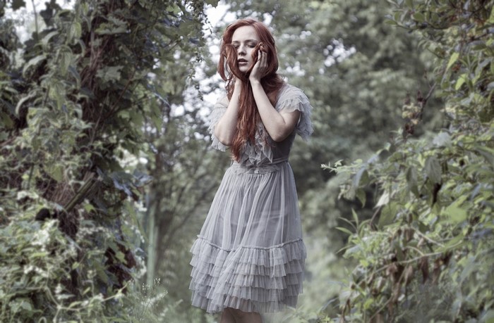 Redhead woman in a grey dress in a forest