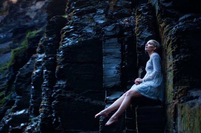 Woman in blue dress sitting on rocks