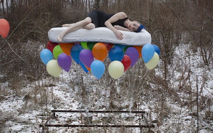 Woman lying on mattress floating with balloons