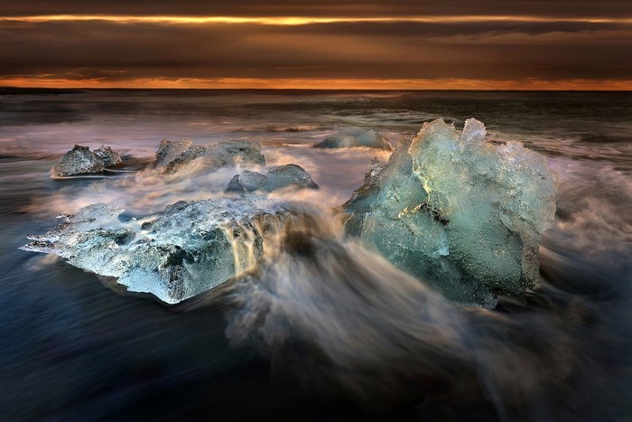 Icebergs on a black sand beach at sunset