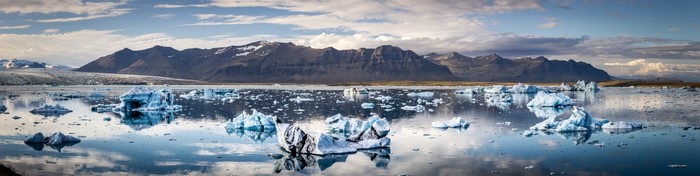 Icebergs floating in a glacial lake with mountains in the background