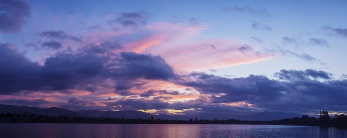 Sunset over a calm lake with mountains and colorful clouds