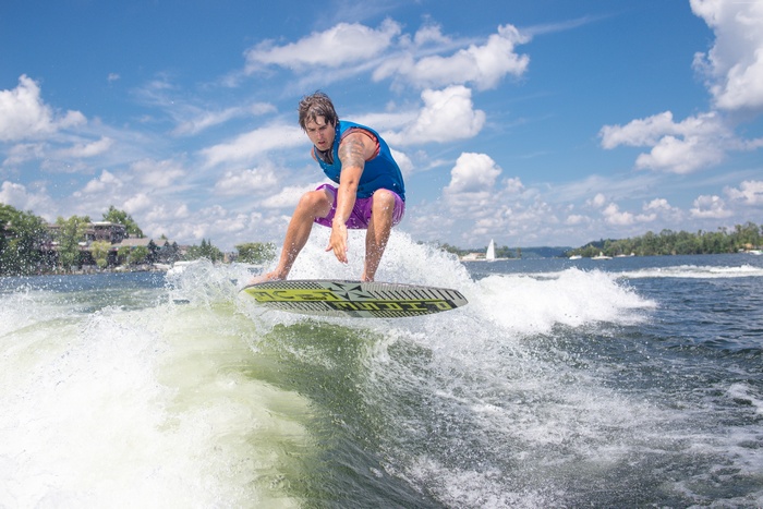 Man wakesurfing on a lake with houses in the background