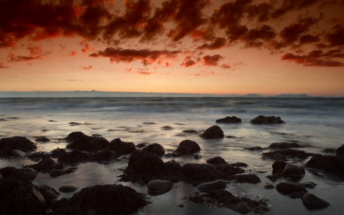 Sunset over the ocean with rocky shore