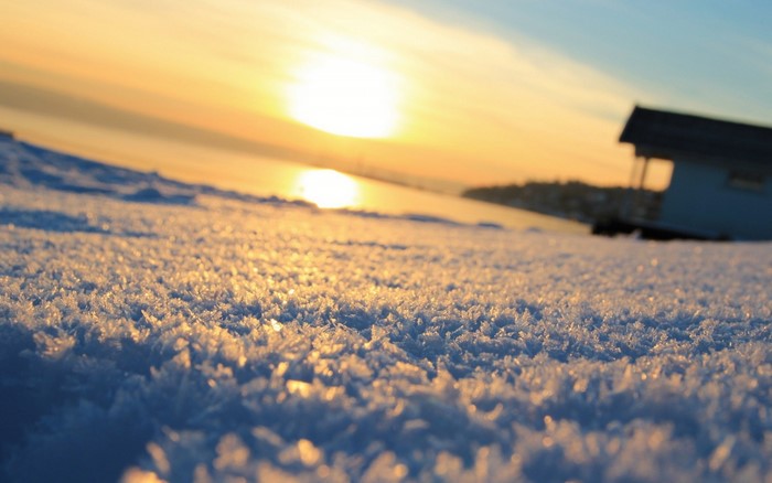 Snowy landscape with sunset and a small building