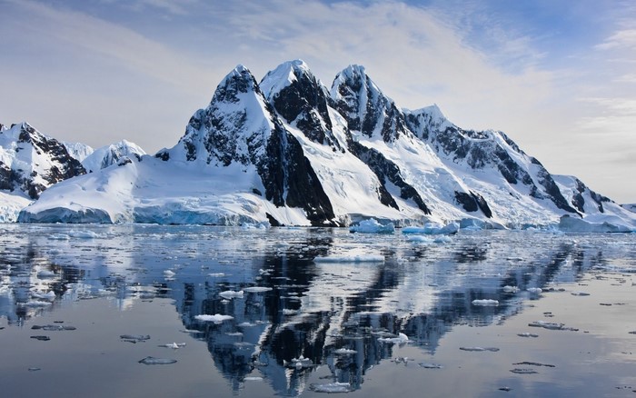 Snow-covered mountains reflected in icy water