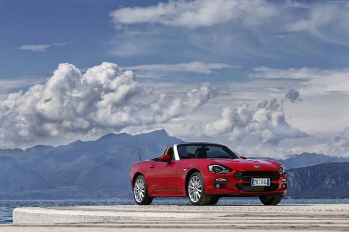 Red FIAT 124 Spider convertible by a lake with mountains