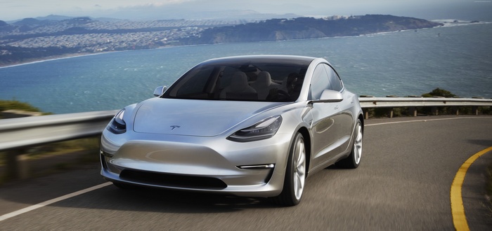 Silver Tesla Model 3 Prototype driving on a coastal road