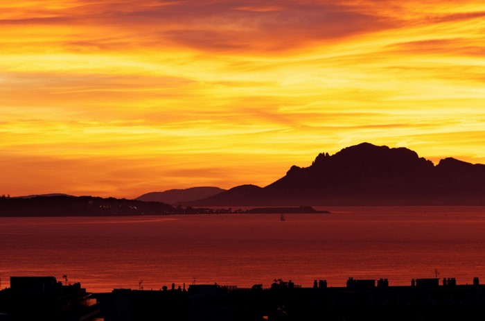 Sunset over the sea with mountains and city