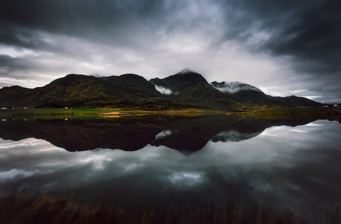 Mountains reflected in a lake under a cloudy sky
