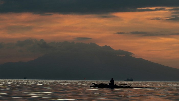 Silhouette of a person in a boat at sunset over the sea