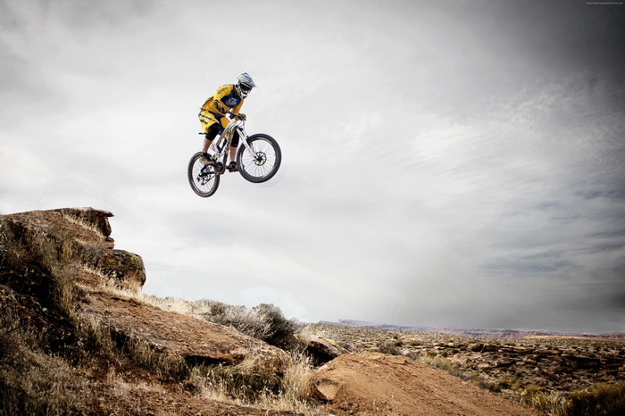 Motocross rider performing a jump in a desert landscape