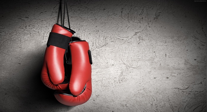 Red boxing gloves hanging on a concrete wall