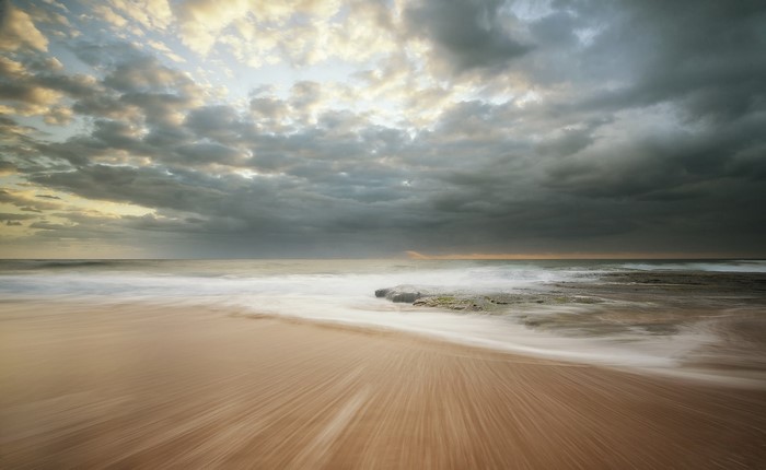 Ocean waves crashing on a sandy beach at sunset