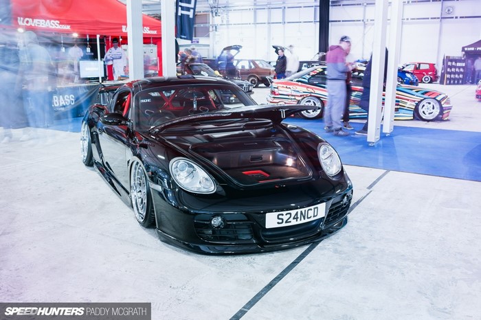 Black Porsche Cayman S with custom modifications at an auto show