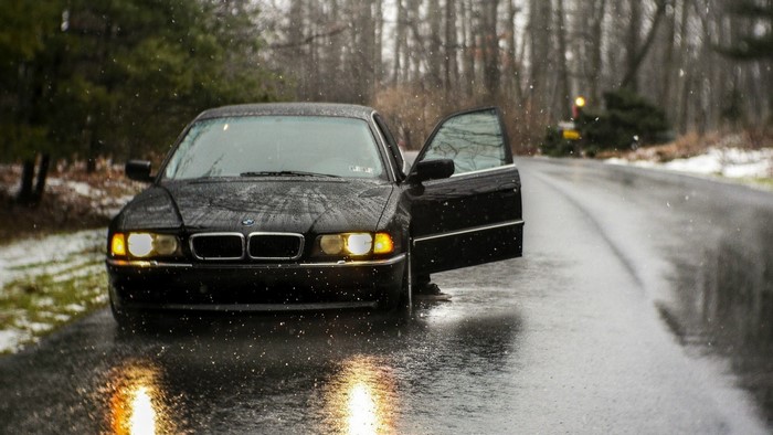 Black BMW 740 parked on a wet road in the snow