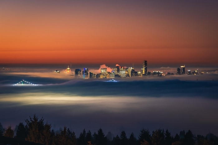 Cityscape shrouded in fog at sunset with bridge