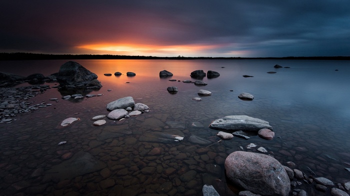 Rocky lake shore at sunset with colorful sky