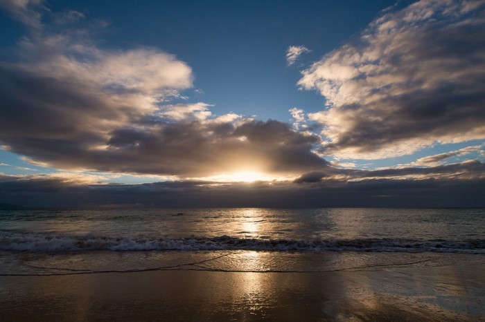 Sunset over the ocean with clouds and beach
