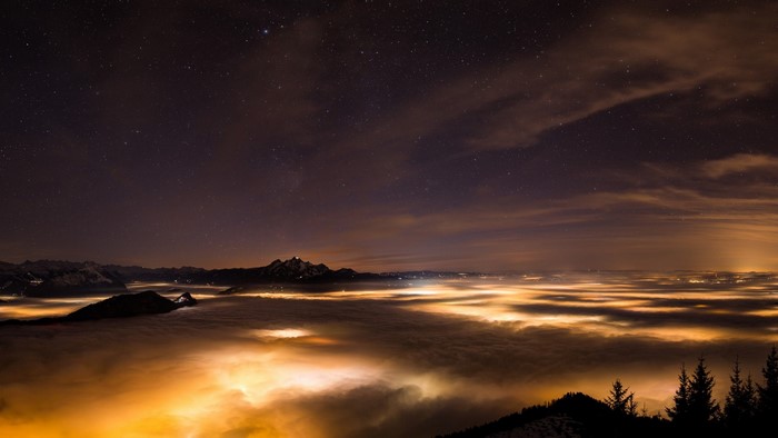 Night sky over a sea of clouds and mountains
