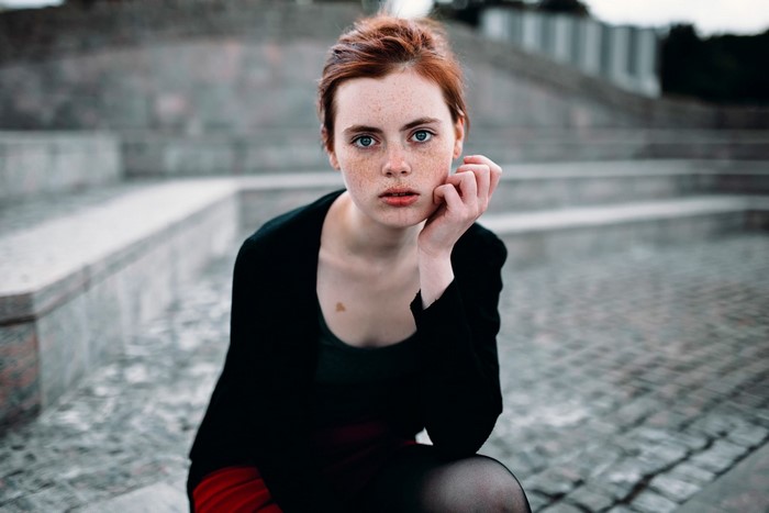 Redhead woman with freckles sitting outdoors