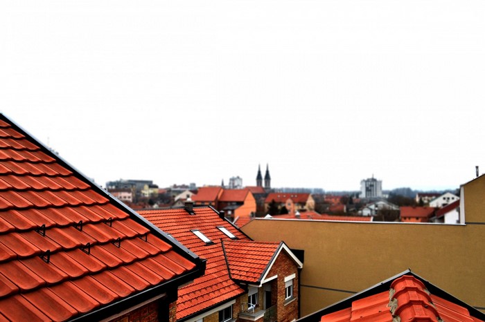 Rooftops of a residential area with church spires in the distance