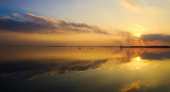 Sunset over calm water with reflections