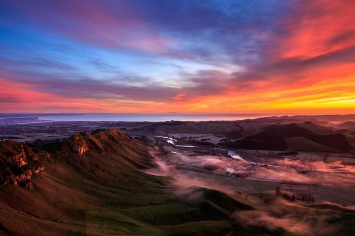Dramatic sunset over rolling hills and a river