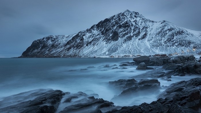 Snowy mountains and rocky coast with ocean waves