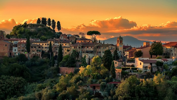 Italian village at sunset with rolling hills and clouds