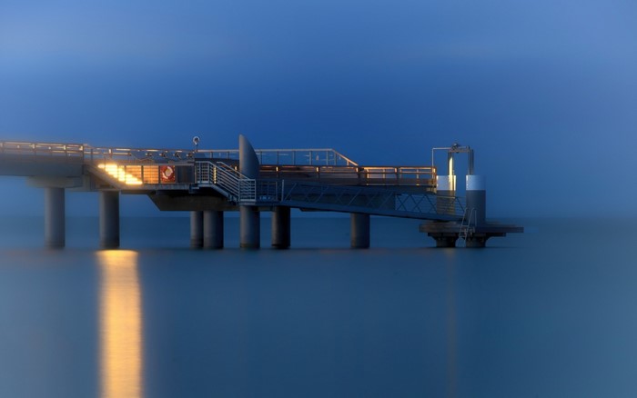 Pier over the ocean at dusk with reflections