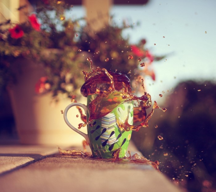 Coffee splashing out of a mug with flowers in background